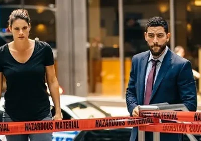 Pôster de FBI: Agentes sérios Maggie e Omar, atrás de fita HAZARDOUS MATERIAL em cena urbana, com clima tenso.