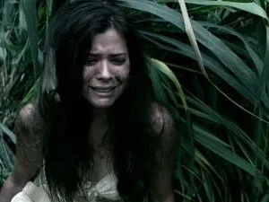 Pôster de Lost: Kate Austen, suja e em prantos, emerge de folhagem densa. O clima é de desespero e sobrevivência.