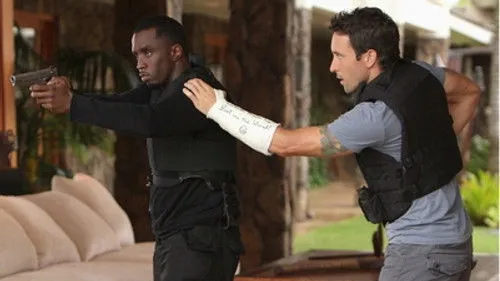 Havaí Cinco-0 – T01E21:Ho'opa'i (Vingança) 1 Hawaii Five-0:Diddy,armado e de colete tático,aponta pistola. McGarrett,com braço engessado,o guia. Cena de ação tensa.